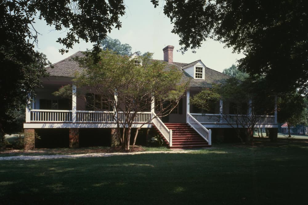 A large, two-story house with a porch, surrounded by greenery.