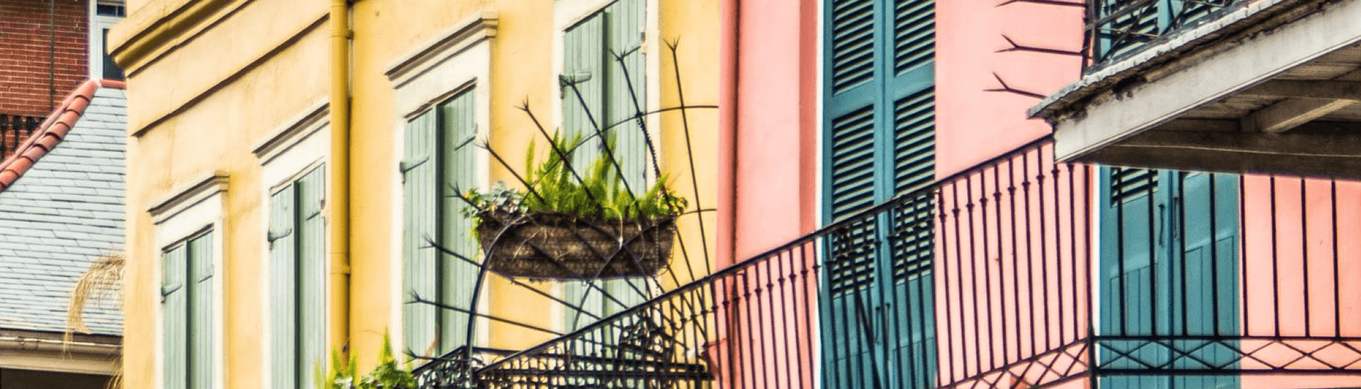 Colorful building facades with green shutters and a hanging planter.