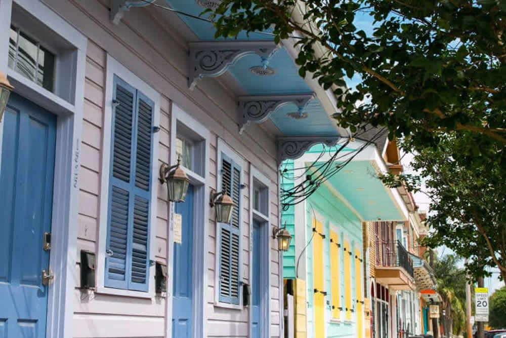 Colorful facades of houses with blue shutters and vintage lanterns under a bright sky.