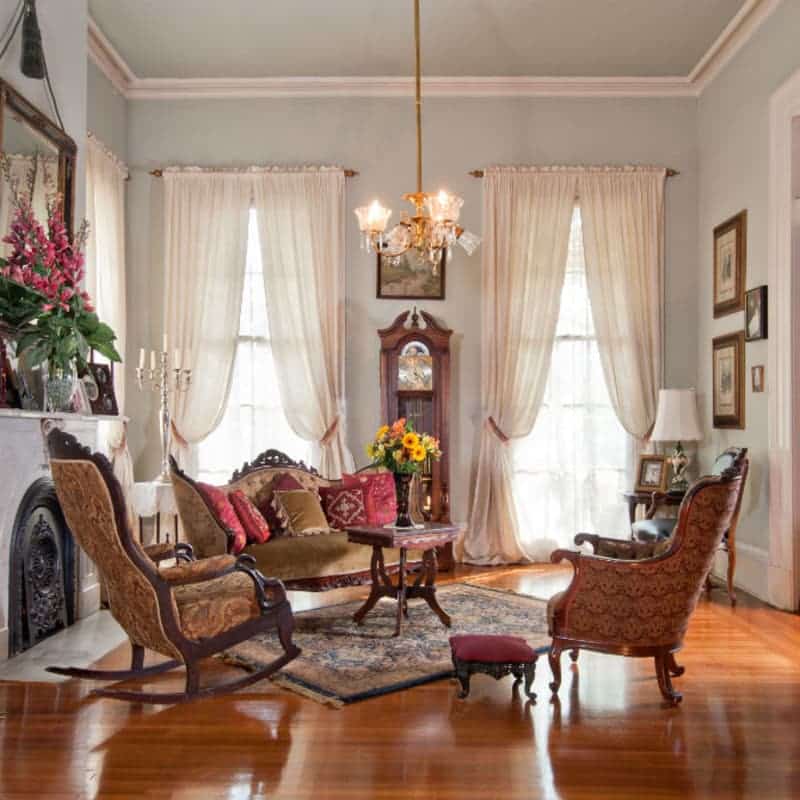 A cozy, elegantly decorated living room with floral arrangements and vintage furnishings.