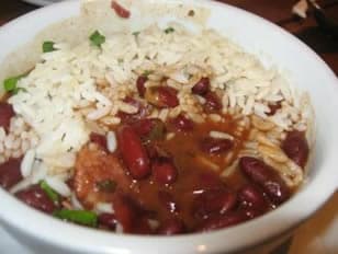 A bowl of rice topped with red beans in a flavorful sauce.