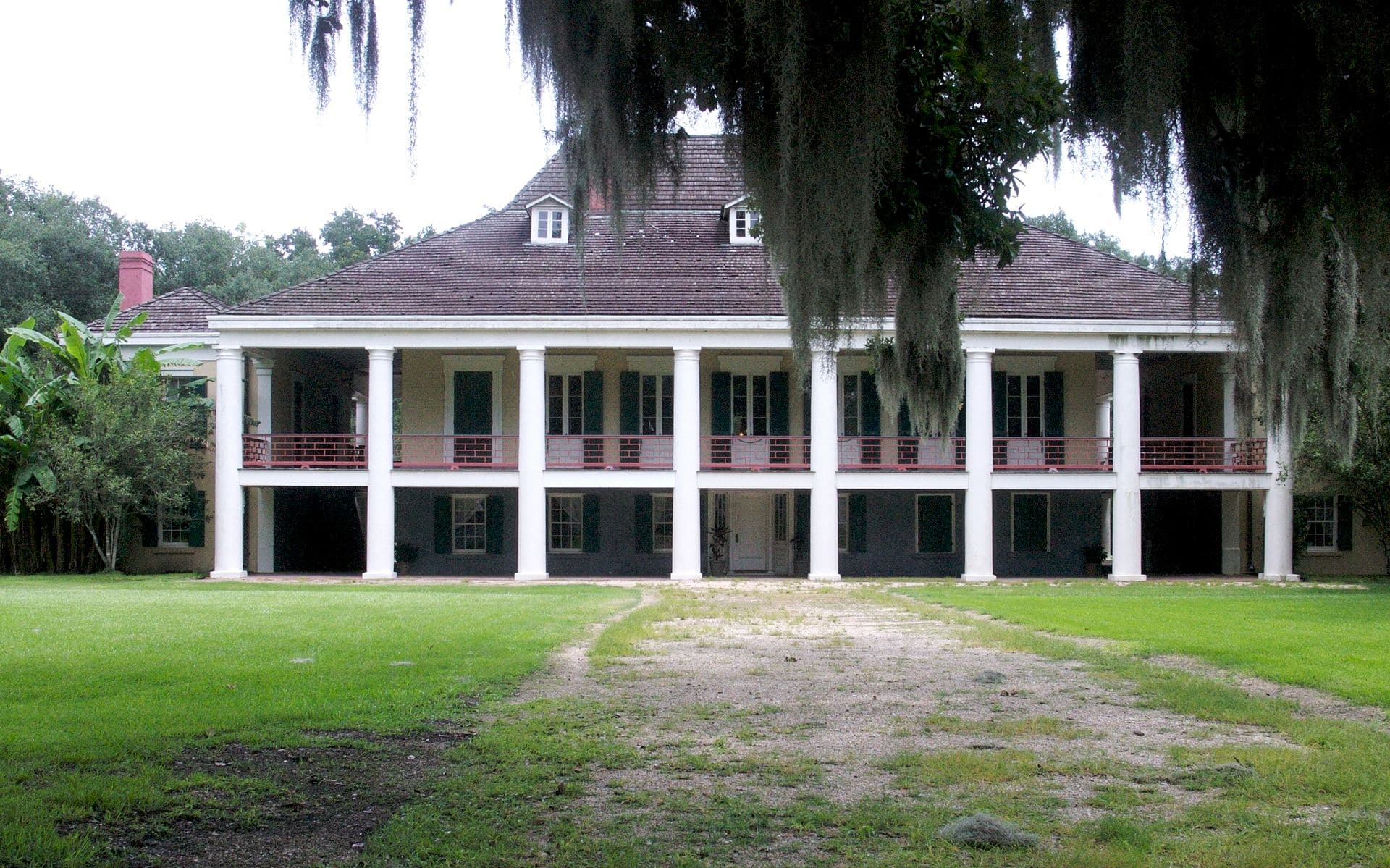 Antebellum-style plantation house with large columns and a grassy lawn. Antebellum-style plantation house with large columns and a grassy lawn.