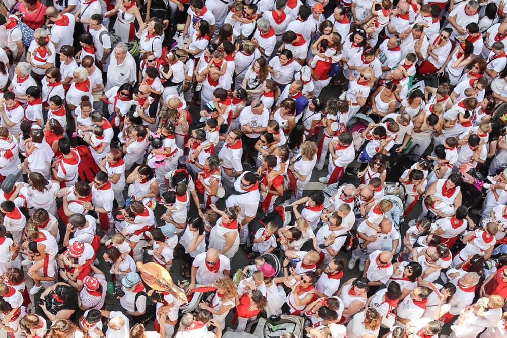 A large, densely packed crowd wearing mostly white with red accents gathers in a public space.