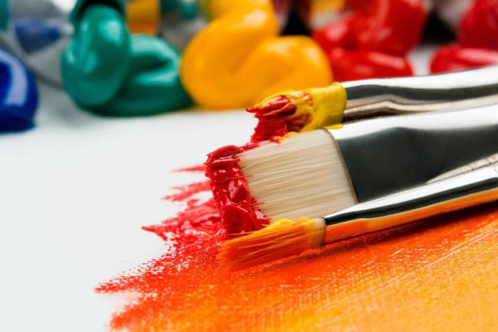 Close-up of paintbrushes resting on vibrant paint strokes.