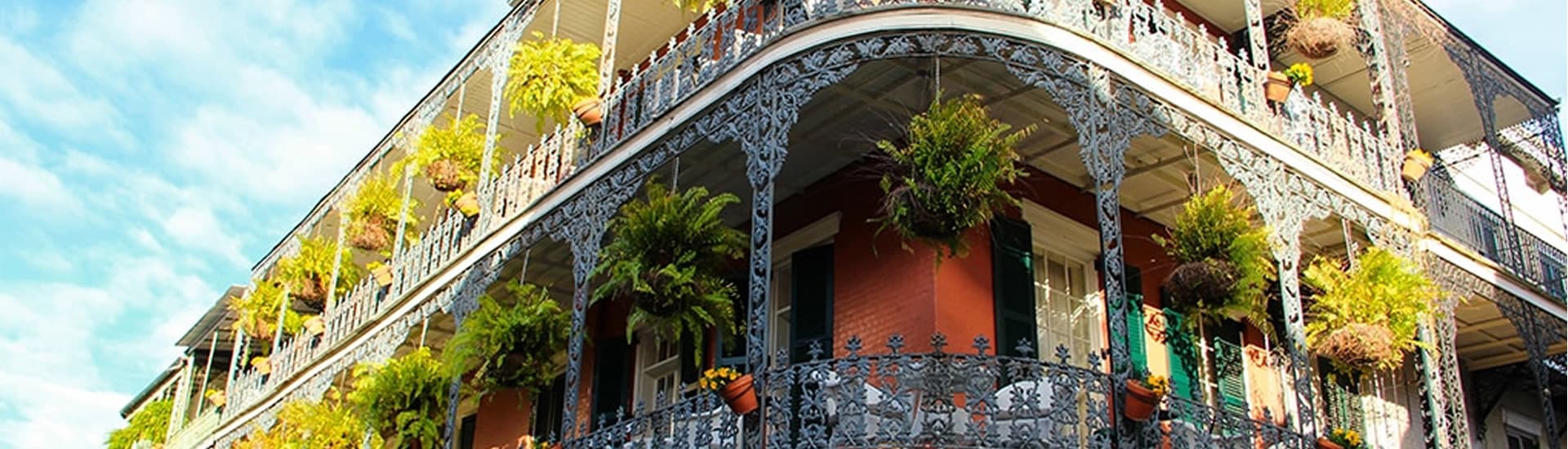 Historic building with intricate ironwork balconies adorned with plants.