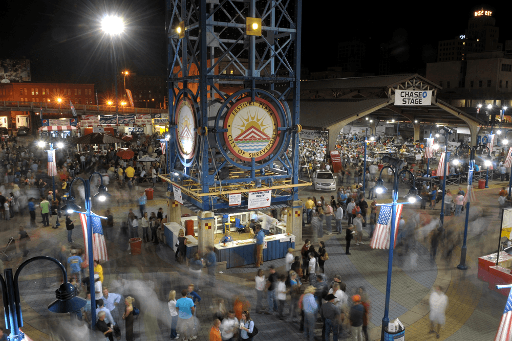 A bustling night market scene with many people enjoying festivities under bright lights.