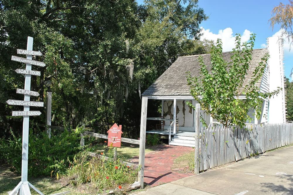 A small white building with a sloped roof surrounded by greenery and directional signs for outdoor activities.