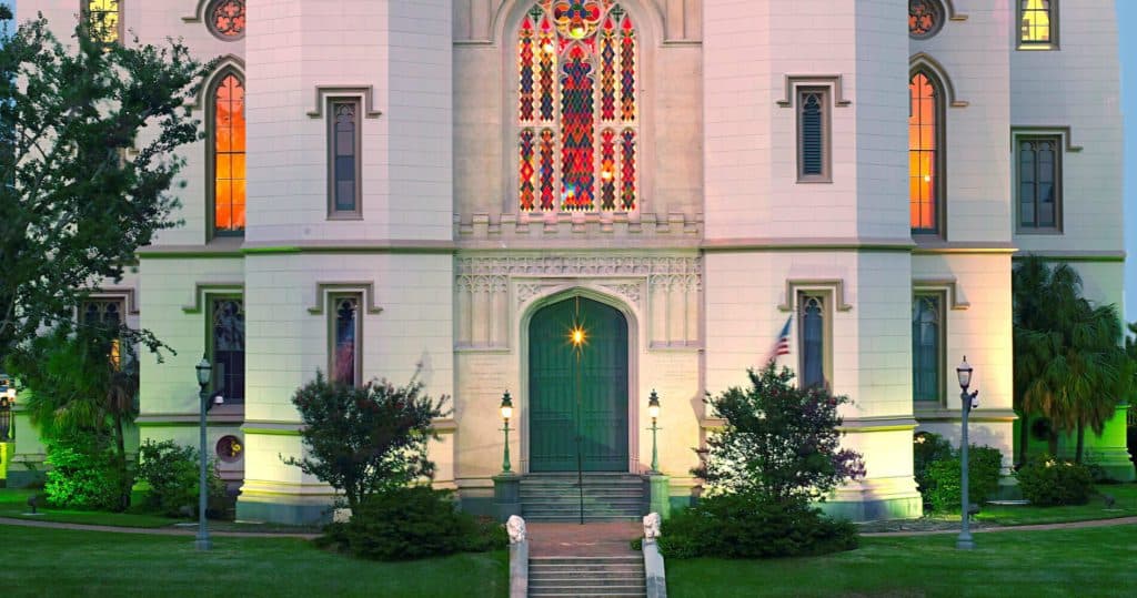 A historic building with a grand entrance, adorned with stained glass windows and surrounded by lush greenery. A historic building with a grand entrance, adorned with stained glass windows and surrounded by lush greenery.
