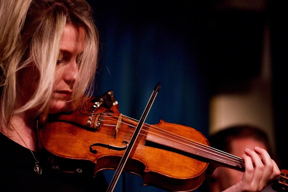 A woman plays the violin, focused and immersed in her music.
