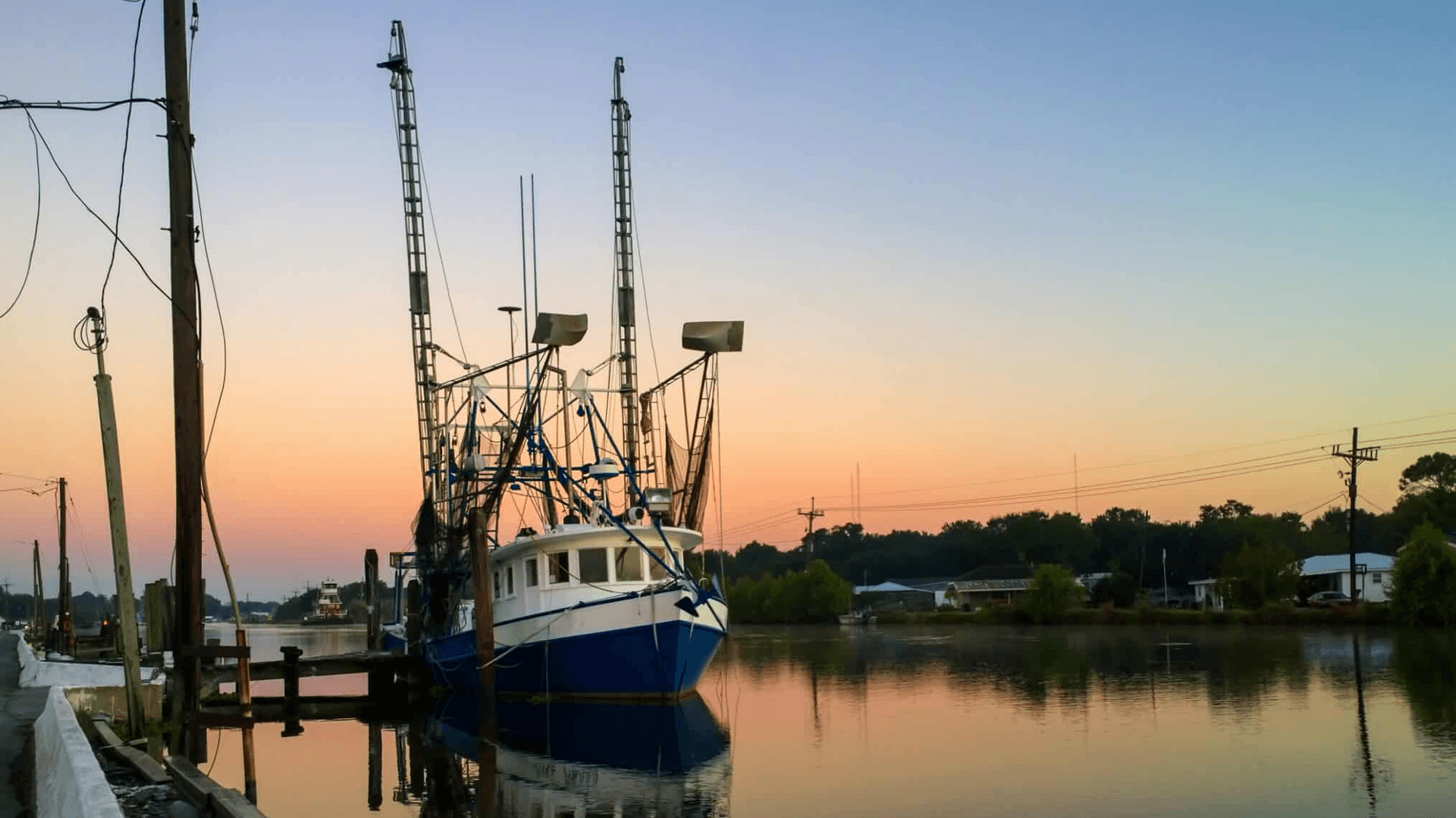 Fishing boat docked at sunset along a calm waterway.