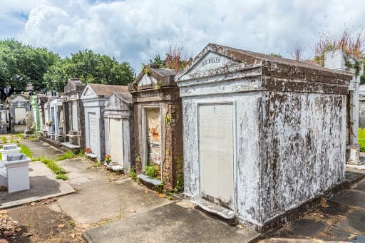 A row of weathered tombs in a cemetery under a cloudy sky.