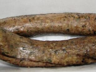 A coiled piece of sausage with a speckled exterior.