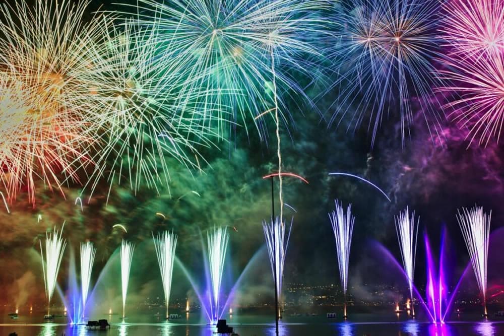 A vibrant display of colorful fireworks illuminating the night sky above a body of water.