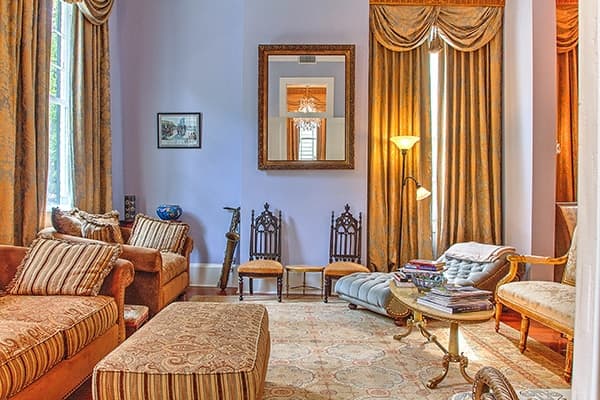 A cozy living room featuring striped sofas, elegant curtains, and a decorative mirror.
