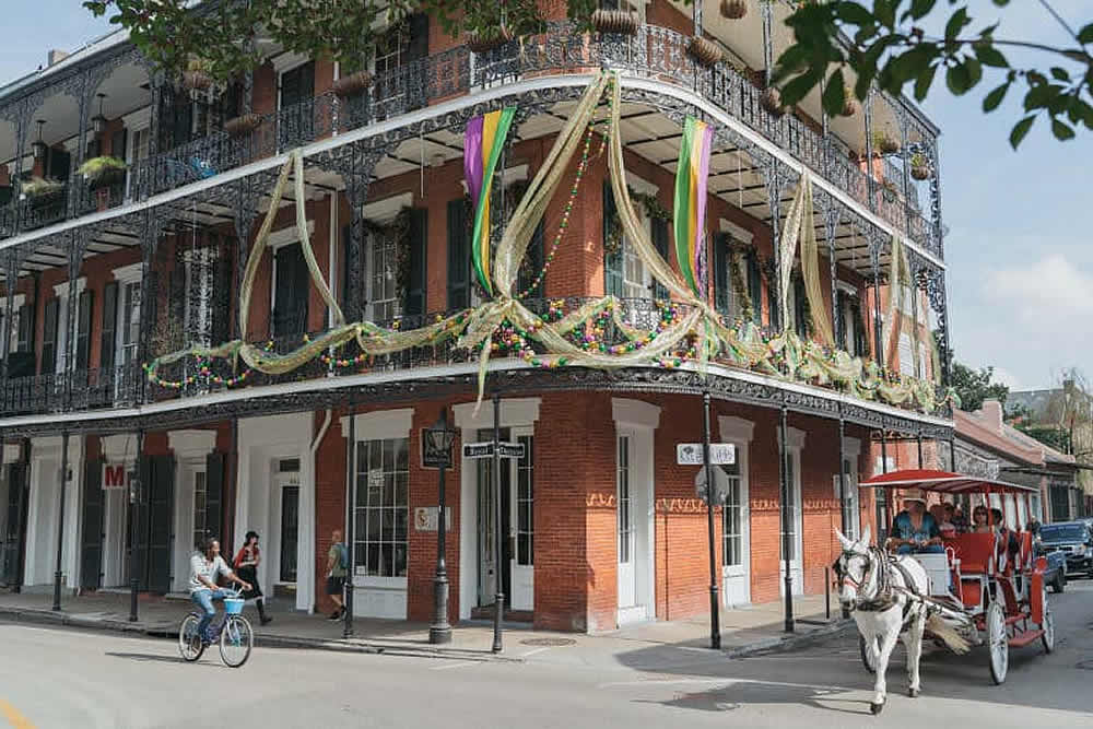 A horse-drawn carriage passes by a festive, decorated building in a vibrant urban setting.