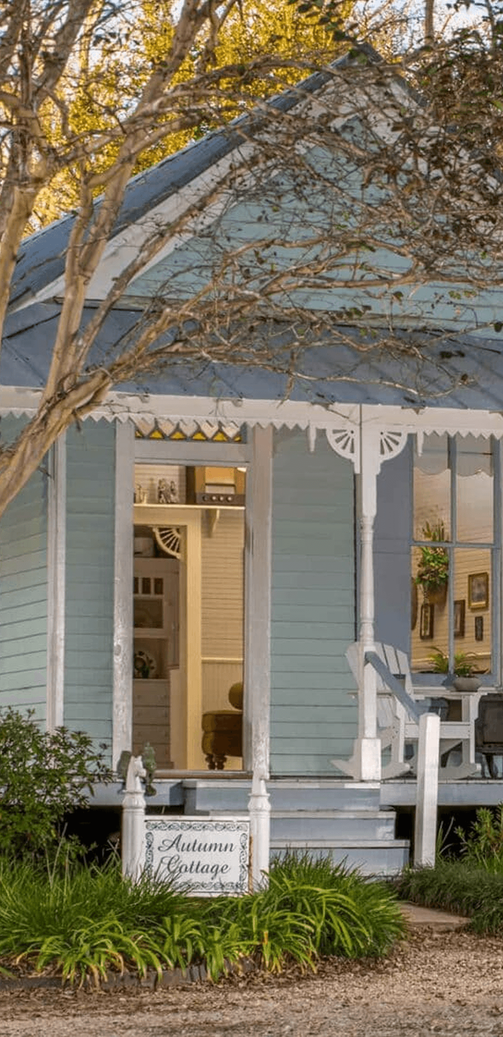 A charming blue cottage with a welcoming porch and a sign reading "Autumn Cottage."